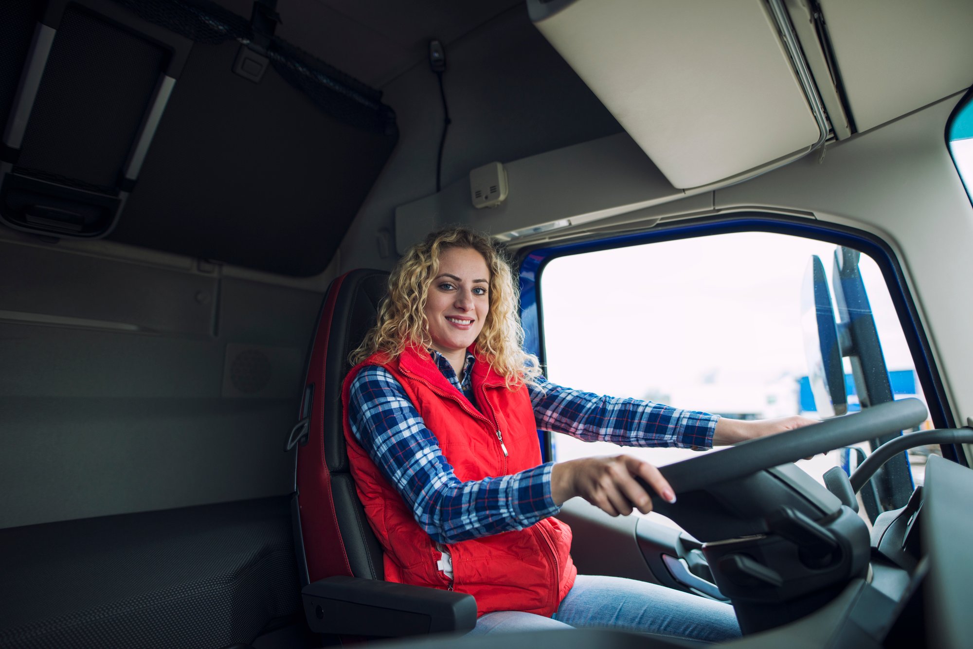 portrait-trucker-sitting-truck-cabin-with-hands-steering-wheel